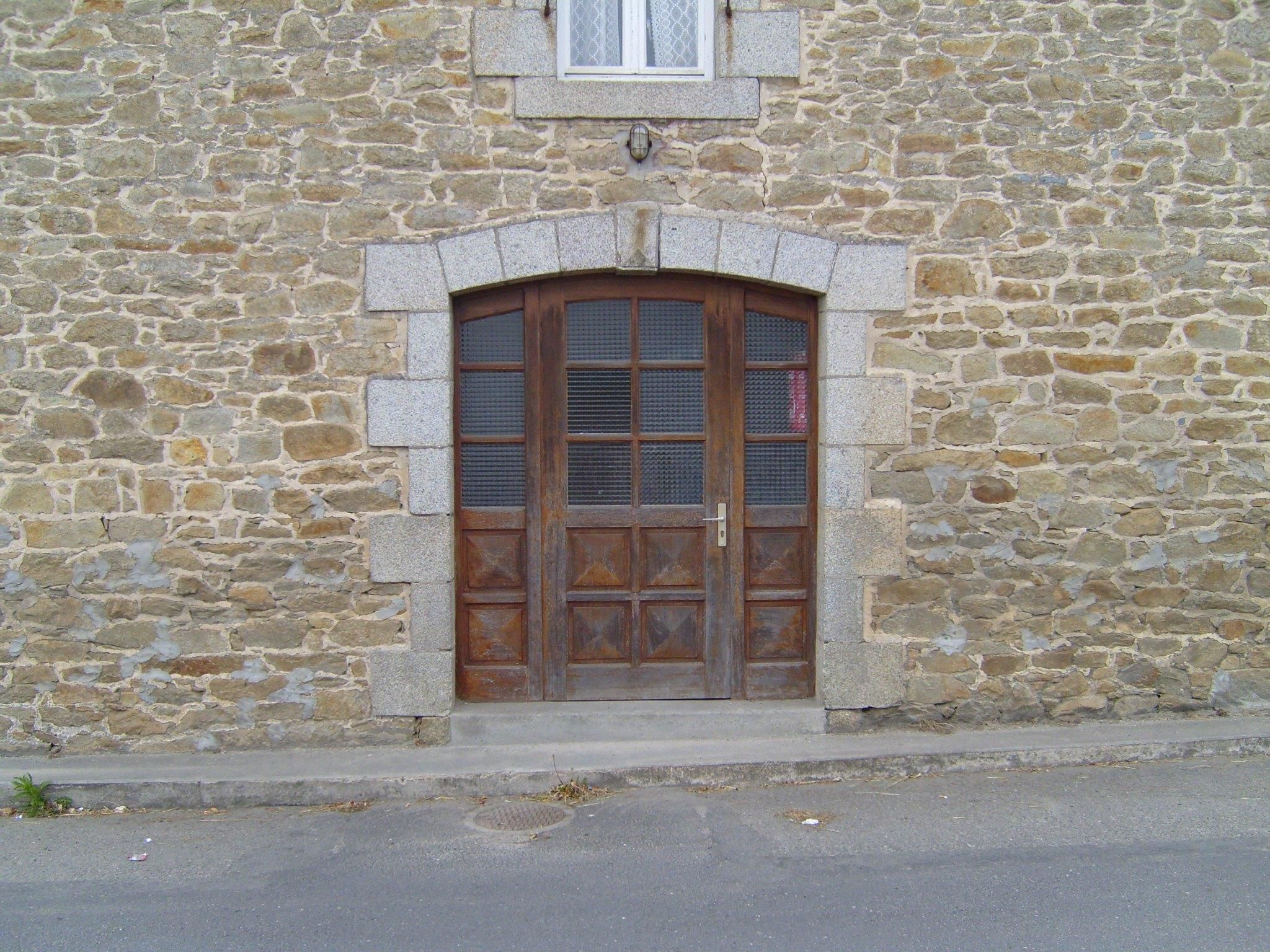 porte d'entrée en bois ancienne, encadrée de granit, sur la façade en pierre d'une maison du Léon