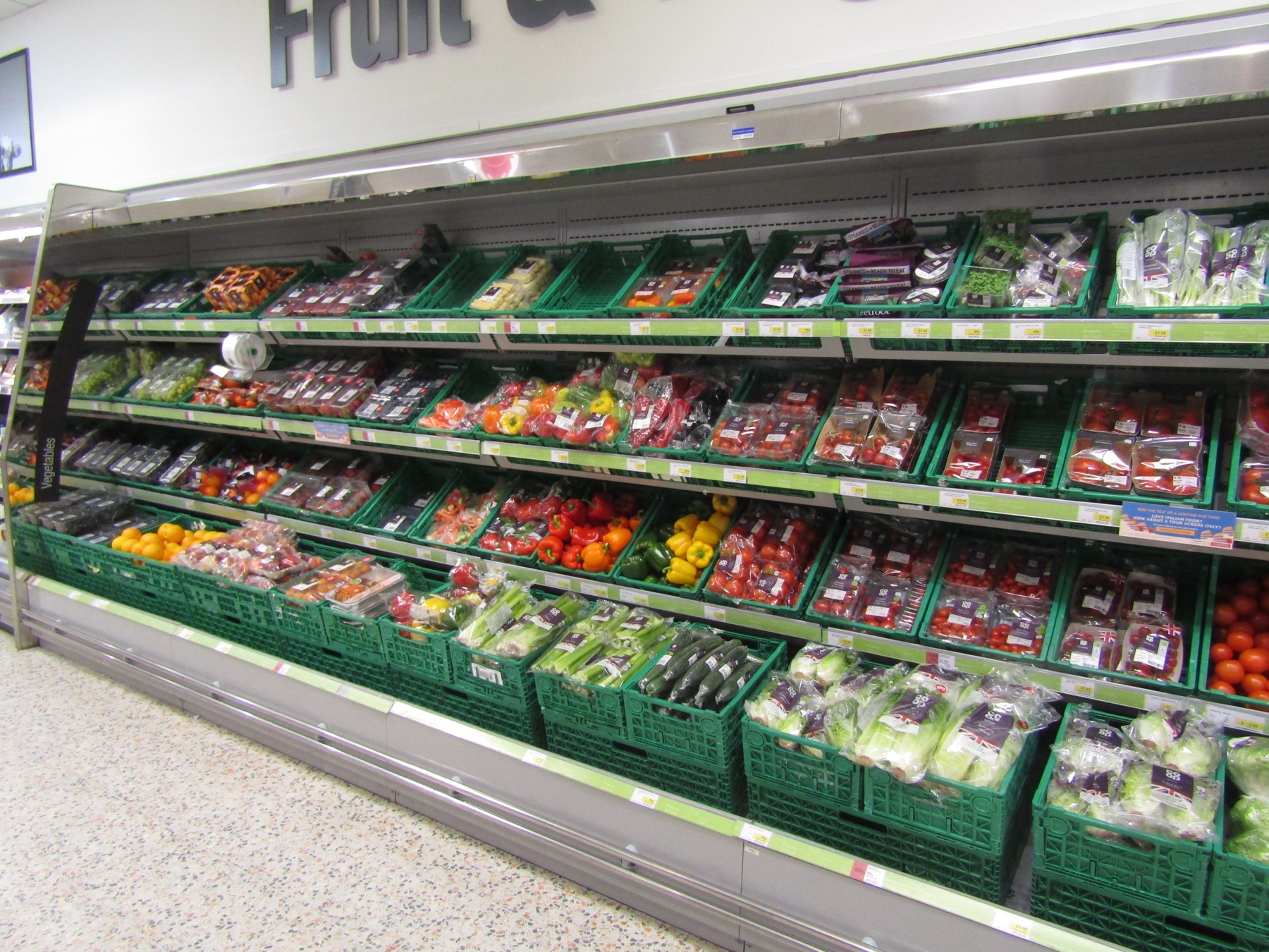 rayon de fruits et légumes frais dans un supermarché, étiquettes de prix et de provenance visibles