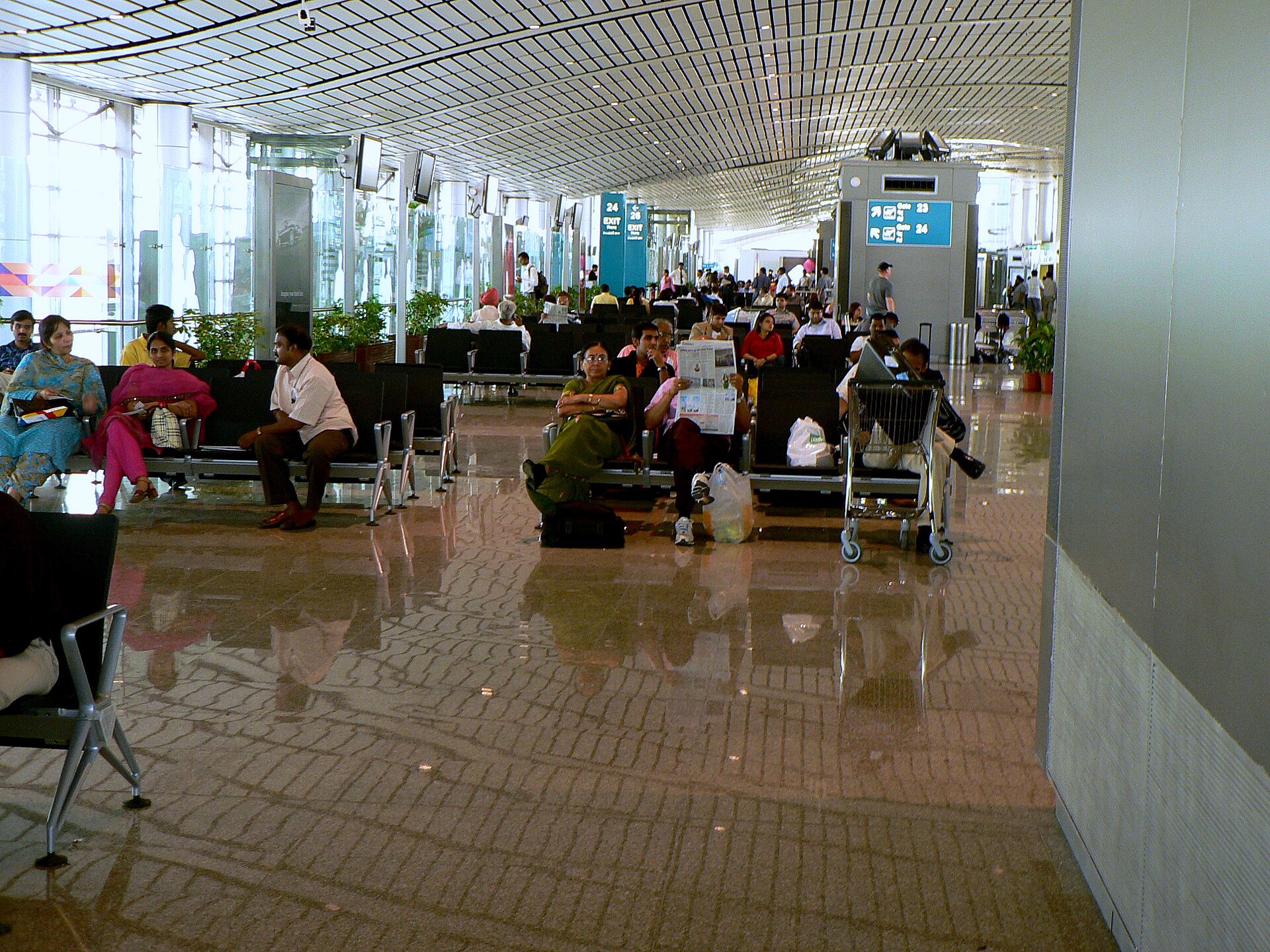 salle d'embarquement d'un aéroport, plusieurs voyageurs assis avec leurs bagages en attendant leur vol