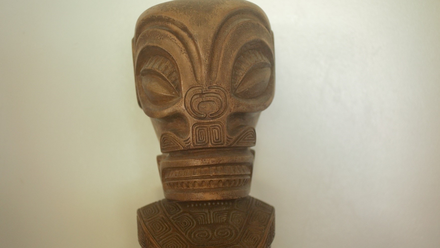 détail d'un tiki polynésien sculpté à la main, visage stylisé aux motifs gravés