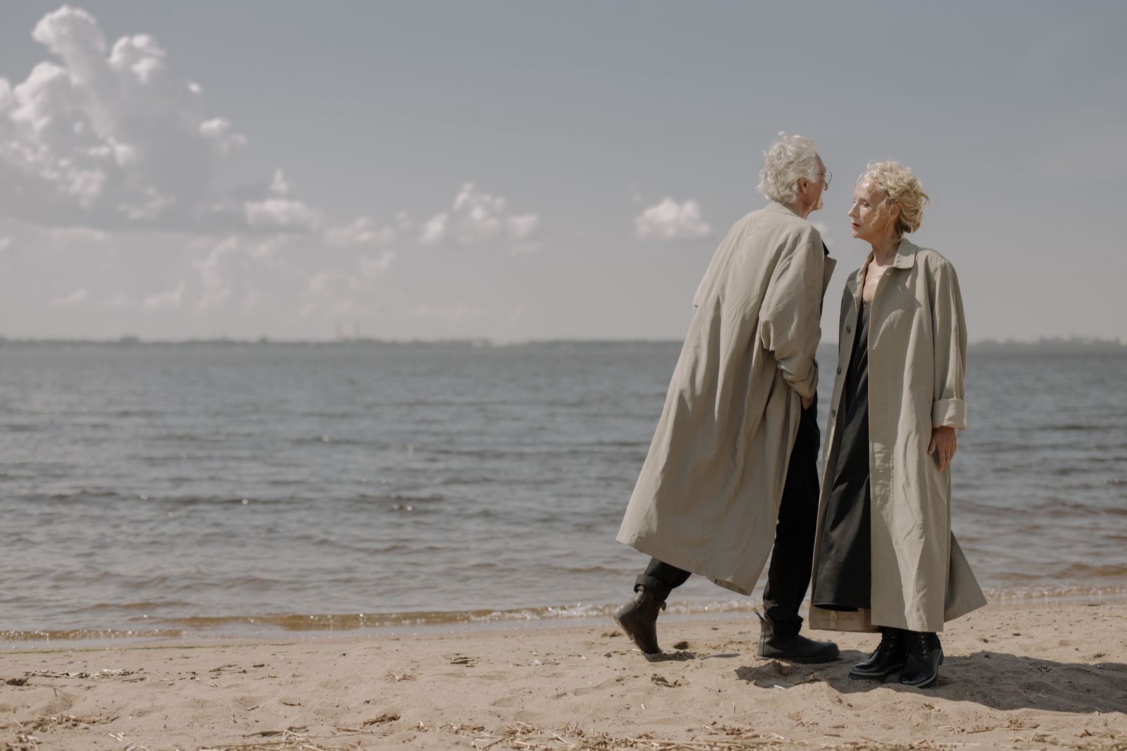 Un couple âgé marche côte à côte sur une plage au bord de la mer