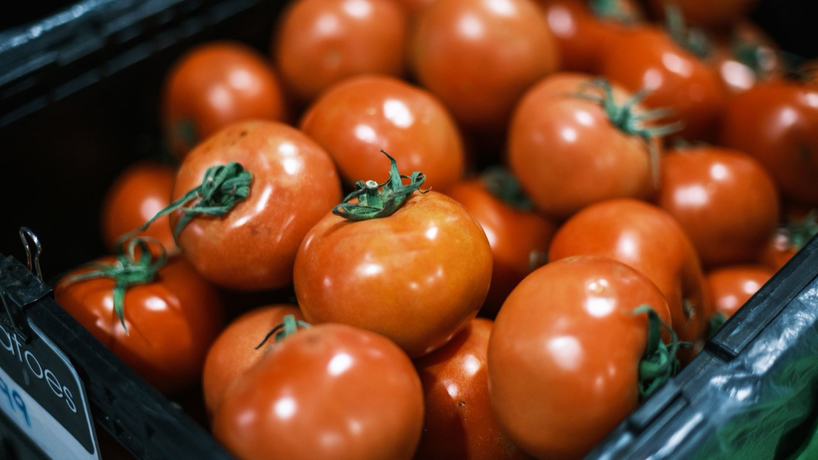 Caisse en bois remplie de tomates bien mûres sur un étal de marché