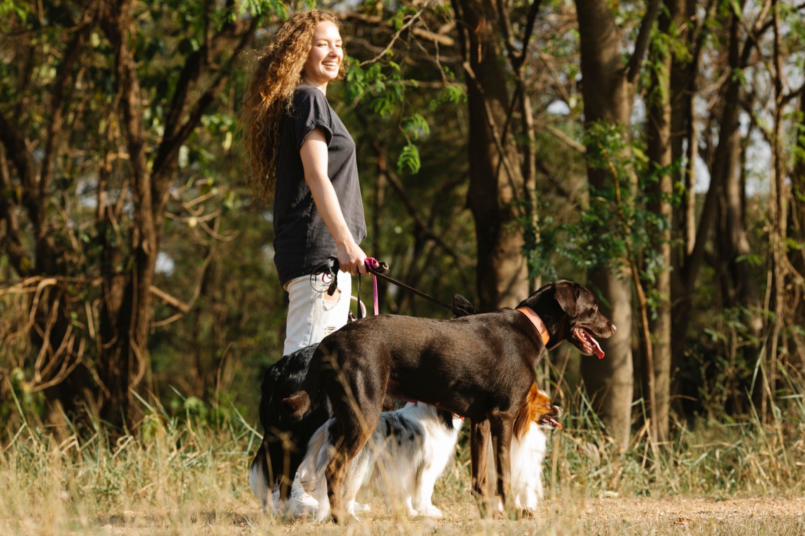 Une femme promène un chien en laisse sur un chemin de campagne